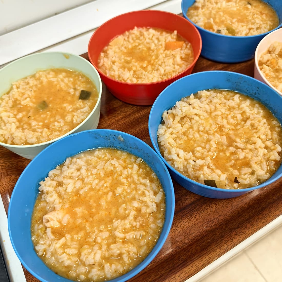 Varios cuencos de colores con arroz caldoso y verdura, listos para servir a los niños