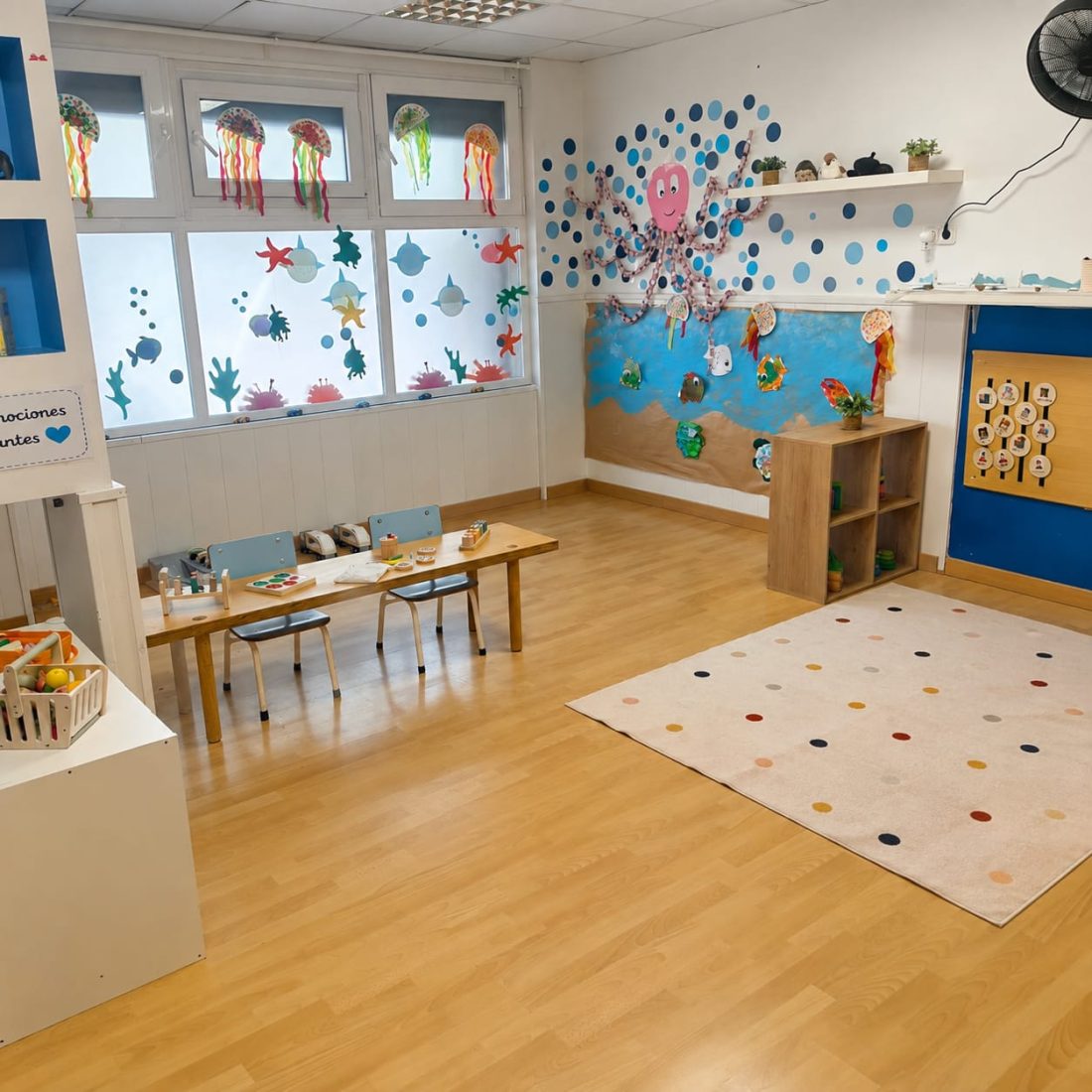 El aula de Poriols con las mesas preparadas para una propuesta y el rincón de juego simbólico