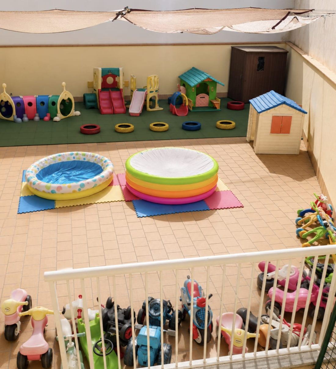 Patio exterior de Meraki con las dos piscinas de verano montadas, la casita de juego, el tobogán y los correpasillos